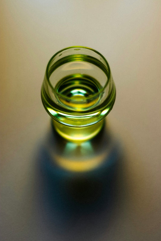 A glass of yellow liquid casts a shadow.
